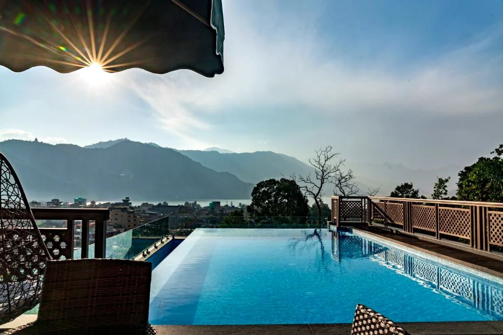 The infinity pool with the sun over the hills