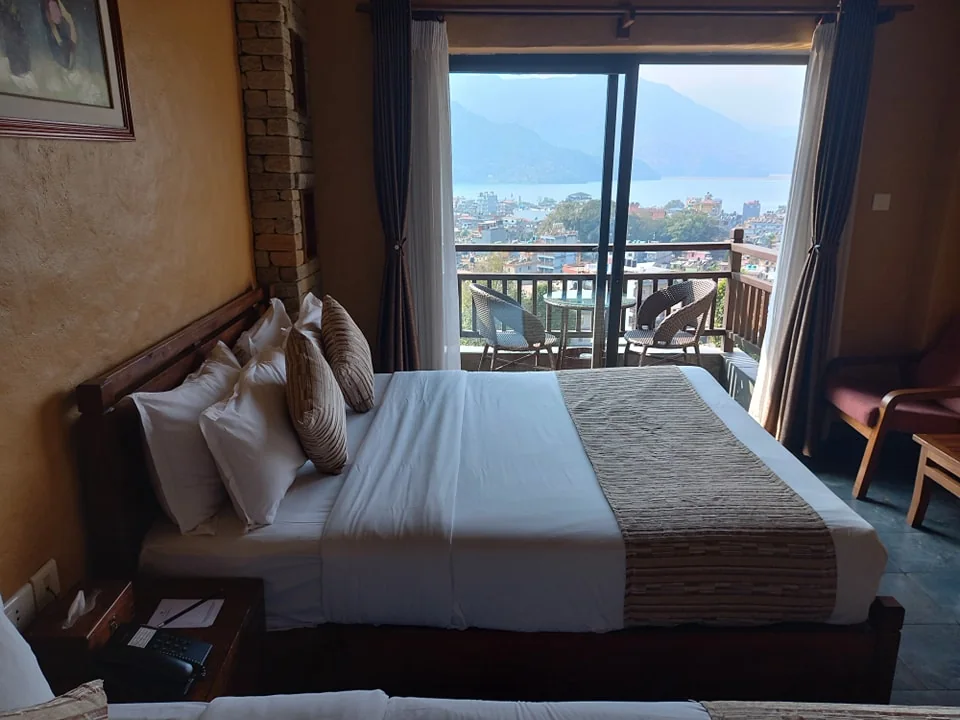 A carved bed facing a balcony with a lake view